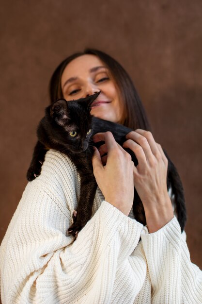 Mujer joven con una camisa blanca sostiene un gatito en sus brazos