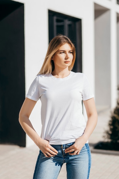 Mujer joven en camisa y jeans posando al aire libre