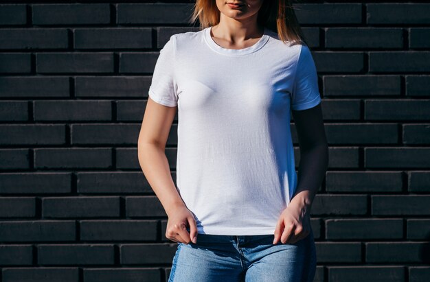 Mujer joven en camisa y jeans posando al aire libre