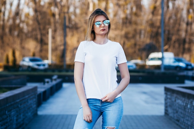 Mujer joven en camisa y jeans posando al aire libre