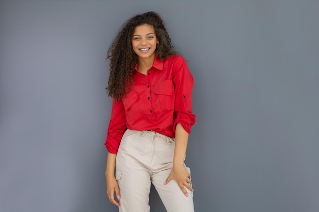 mujer joven, en, camisa roja, posición, contra, gris, pared