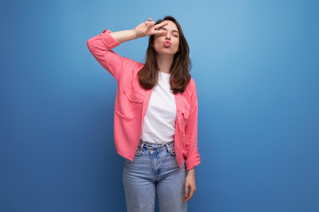 Mujer joven en una camisa rosa y jeans con una sonrisa en un estudio de fondo aislado