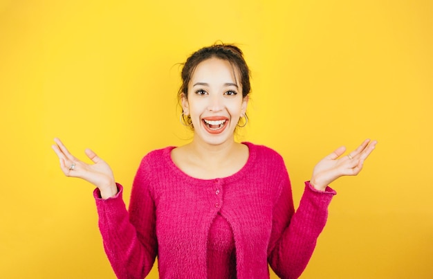 Mujer joven en camisa rosa sin saber qué hacer levantando las manos Actitud de mujer joven Expresión de fondo de color de tono amarillo de personas normales Concepto de maqueta con personas