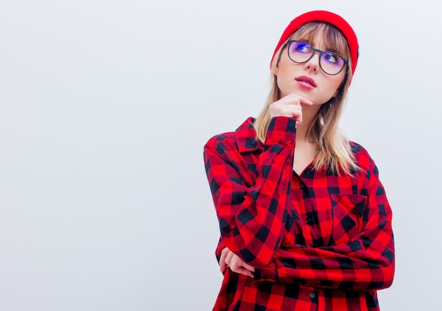 Mujer joven en camisa y sombrero rojos con los vidrios