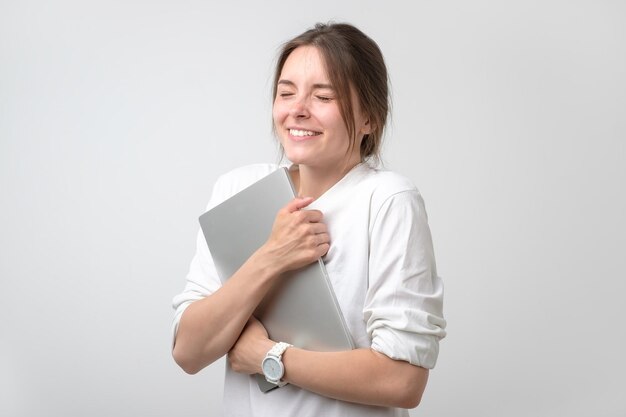 mujer joven, en, camiseta blanca, abrazar, computador portatil