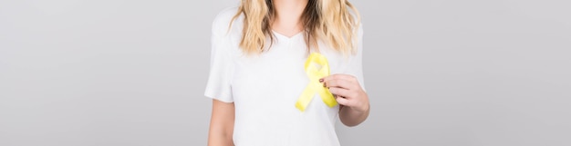 Mujer joven en camiseta blanca con símbolo de conciencia de cinta amarilla para suicidio, cáncer óseo sarcoma, cáncer de vejiga, cáncer de hígado y cáncer infantil