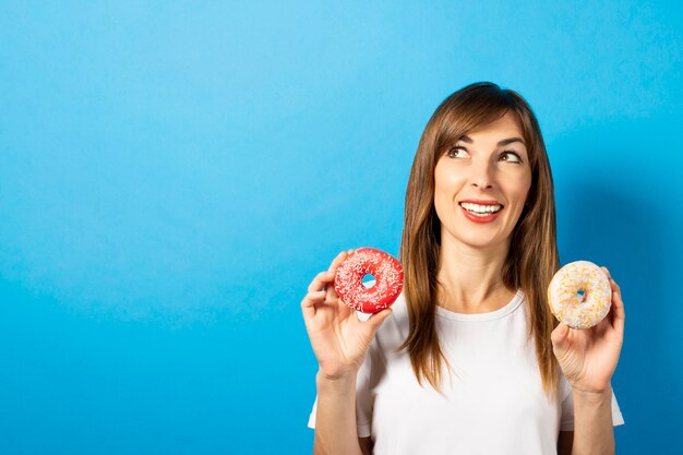 Mujer joven en una camiseta blanca tiene donas aislado