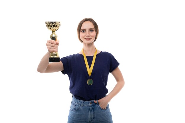 Una mujer joven en una camiseta y jeans sostiene una copa de oro