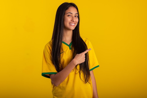 Mujer joven con la camiseta del uniforme oficial de la selección brasileña de fútbol en la Copa Qatar 2022 en una foto de estudio hincha brasileño