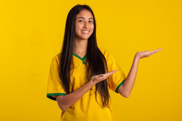 Mujer joven con la camiseta del uniforme oficial de la selección brasileña de fútbol en la Copa Qatar 2022 en una foto de estudio hincha brasileño