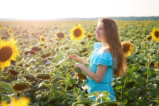 Mujer joven en campo de girasol se divierte