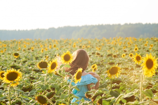 Mujer joven en campo de girasol se divierte