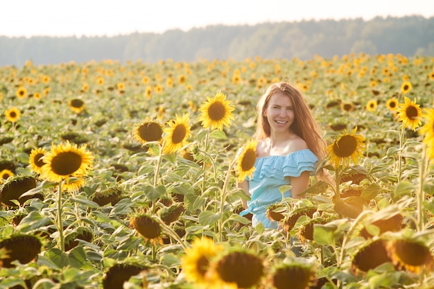 Mujer joven en campo de girasol se divierte