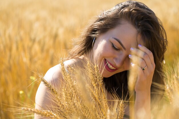 Mujer joven en campo de trigo al atardecer