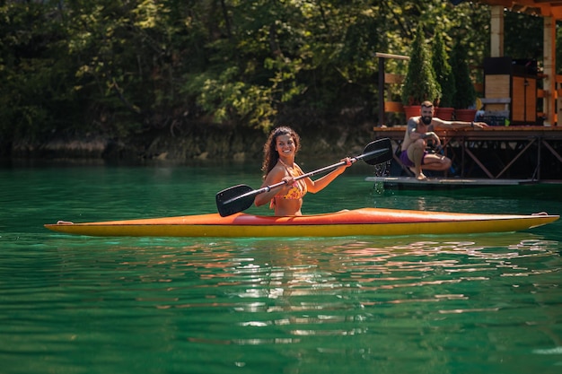 Mujer joven canotaje en un lago en un día de verano