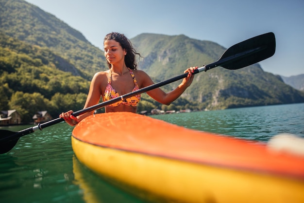 Mujer joven canotaje en un lago en un día de verano