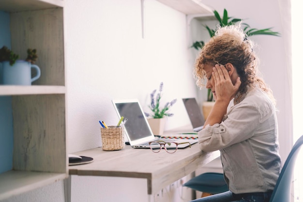 Mujer joven cansada toca rigidez en el cuello sintiéndose herida dolor de espalda articular frotando masajeando músculos tensos sufren de dolor de fibromialgia después de un largo estudio de trabajo en computadora en una postura incorrecta sentada en un sofá en casa