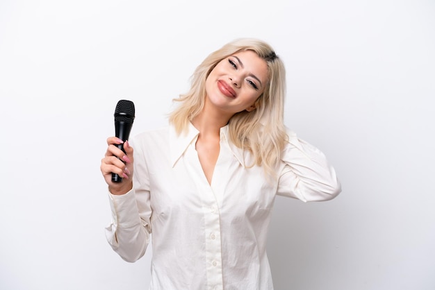 Mujer joven cantante recogiendo un micrófono aislado sobre fondo blanco riendo