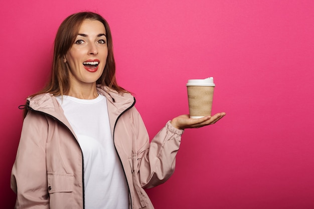 Mujer joven con cara de sorpresa sosteniendo una taza de papel con café