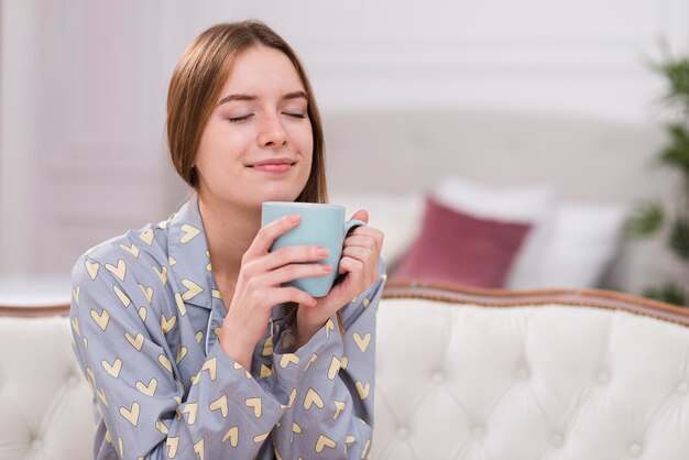 Mujer joven en casa bebiendo té