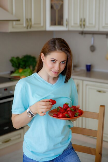 mujer joven en casa en la cocina comiendo fruta