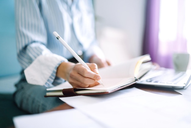 Mujer joven en casa escribiendo y trabajando con Notebook. Freelancer trabaja y toma notas.