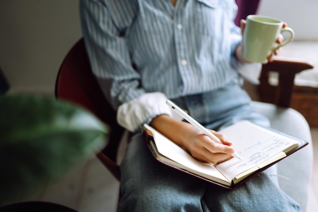 Foto mujer joven en casa escribiendo y trabajando con notebook. freelancer trabaja y toma notas.