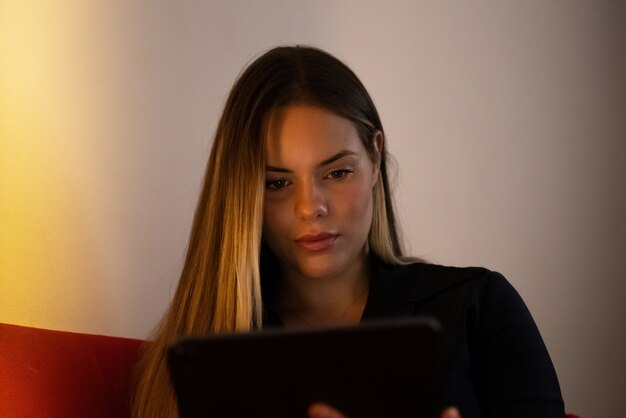 Mujer joven en casa tranquila en el sofá mirando la tableta