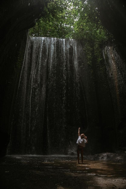 mujer joven en la cascada en la roca Bali Indonesia