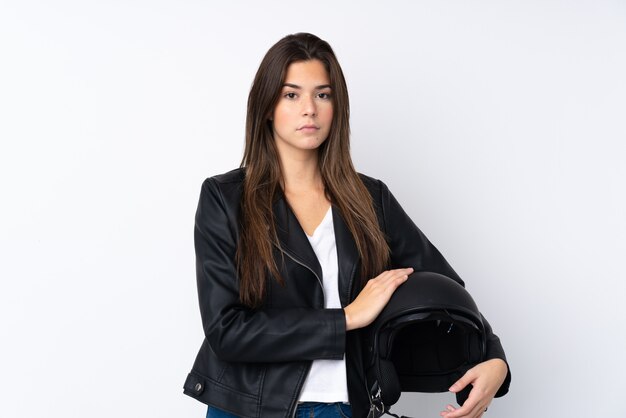 Mujer joven con un casco de moto sobre pared blanca aislada manteniendo los brazos cruzados