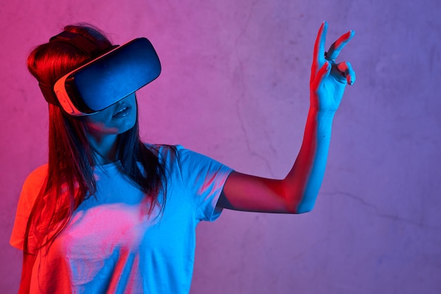 Mujer joven con casco de realidad virtual mientras usa una camiseta blanca