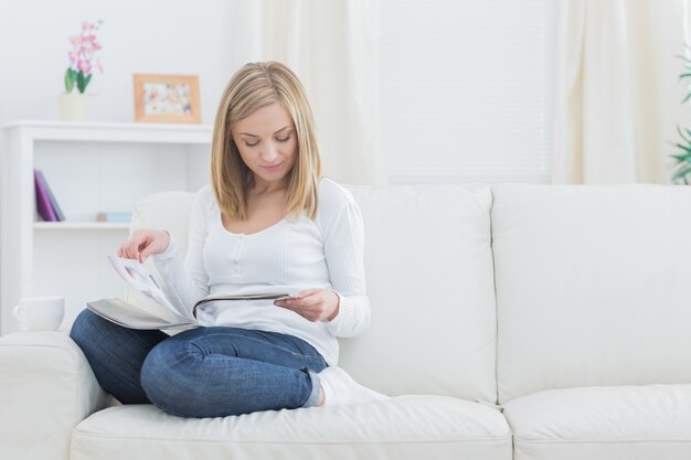 Mujer joven casual leyendo revistas en casa