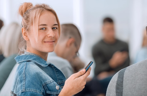 Mujer joven casual con teléfono inteligente mirando a la cámara