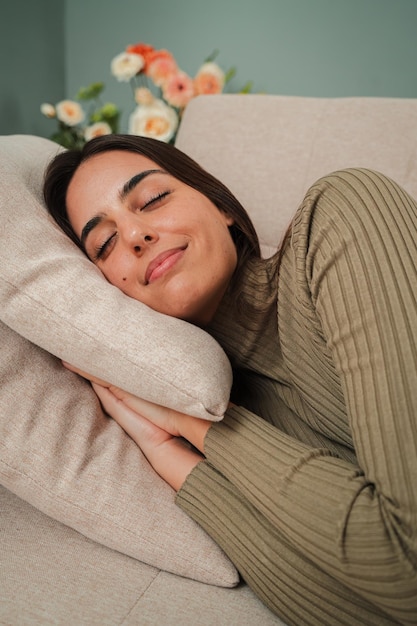 Mujer joven caucásica durmiendo verticalmente durmiendo en el sofá durante el día mujer agotada