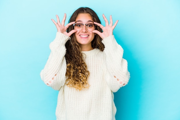 Mujer joven caucásica de pelo rizado aislada manteniendo los ojos abiertos para encontrar una oportunidad de éxito.