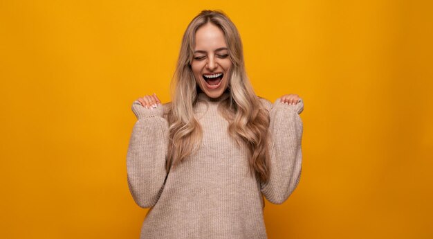 Mujer joven caucásica se regocija emocionalmente entre fondo amarillo