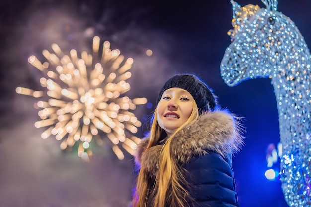 Mujer joven celebrando la Navidad y viendo los fuegos artificiales navideños