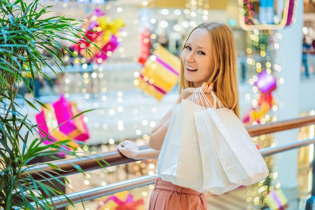 Mujer joven en el centro comercial de navidad con belleza de compras de navidad comprar descuentos en compras de noche de navidad