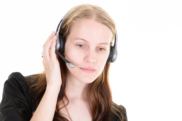 Mujer joven en el centro de llamadas escuchando la mano de un cliente serio en los auriculares de su teléfono