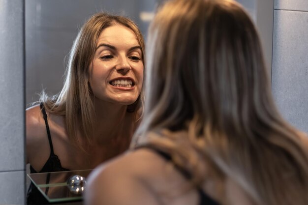 mujer joven, cepillado, ella, dientes, y, reflejado, en, el, espejo