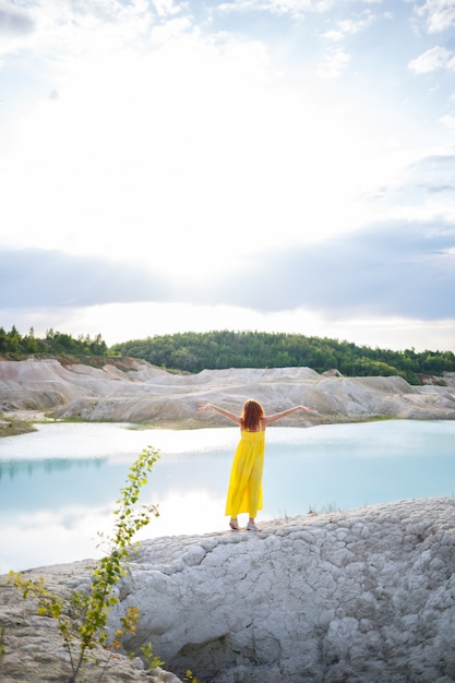 Mujer joven cerca de un lago con agua azul y montañas pedregosas con árboles verdes. Hermosa vista del lago en el bosque