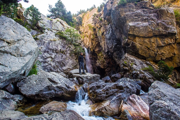 Una mujer joven cerca de una pequeña cascada.