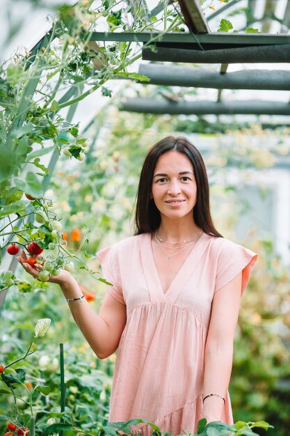 Mujer joven con cesta de vegetación y verduras en el invernadero. Tiempo de cosecha