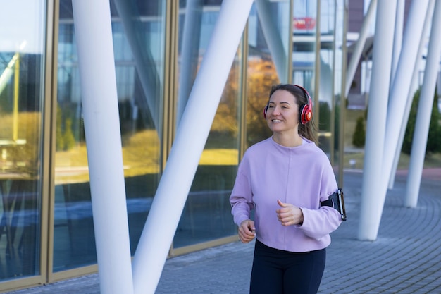 Una mujer joven en chándal corre con auriculares al aire libre