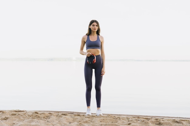 Una mujer joven en chándal se levanta contra el fondo del mar Entrenando por la mañana cuando hace buen tiempo