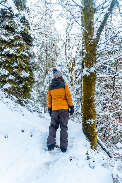 Una mujer joven con una chaqueta amarilla en el bosque nevado del parque natural de Artikutza en oiartzun