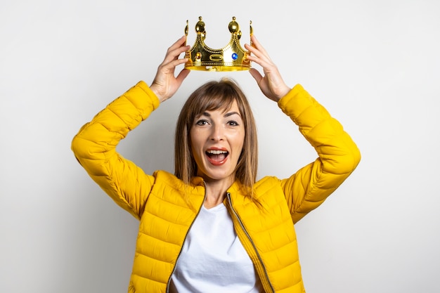 Mujer joven en una chaqueta amarilla y una corona de oro aislada