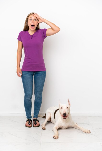 Foto mujer joven con chaqueta amarilla sobre fondo azul sorprendida y apuntando al frente