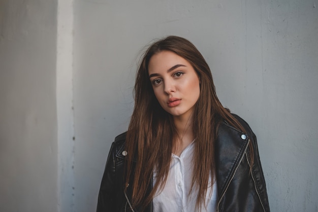 Mujer joven en una chaqueta de cuero negro y blusa blanca