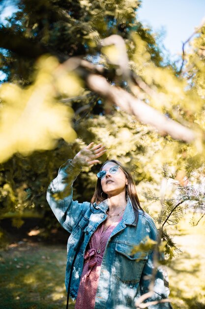 Foto mujer joven con chaqueta mirando hacia otro lado mientras está de pie en el parque